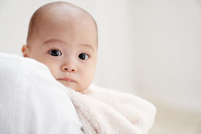 baby in soft towel staring at camera